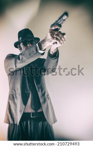 Noir Man Points Gun Up. Man in suit, hat and sunglasses pointing a gun upwards.