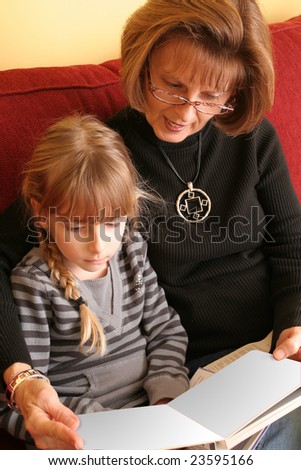 Grandmother and grand-daughter reading a blank book. Clipping path for book included.