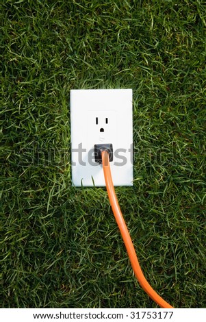 Electrical outlet in grass with extension cord plugged in