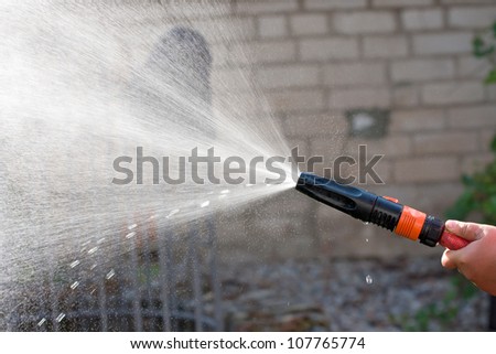 Water spraying from a garden hose in hand