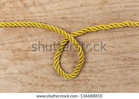 Twisted gold rope loop on a wooden background