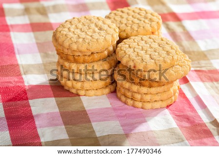 Three stacks of round cookies on a striped tablecloth