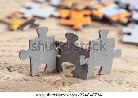 Concept of teamwork: Three jigsaw puzzle pieces on a table joint together. Shallow depth of field