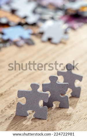 Concept of teamwork: Three jigsaw puzzle pieces on a table. Shallow depth of field