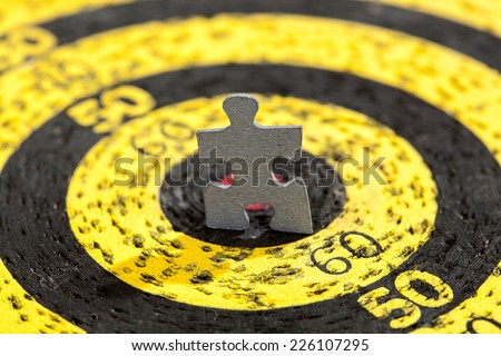 Jigsaw puzzle piece in shape of a standing man in a center of old target