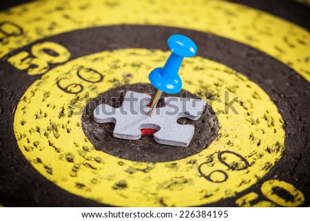 Targeting customers concept: blue pin stuck to a man shape jigsaw puzzle piece on old target board