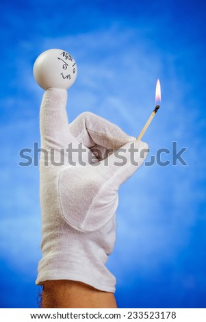 Burning matchstick hold by angry finger puppet over blue background