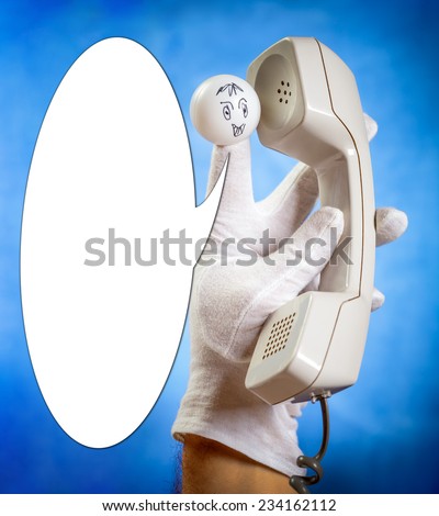 Finger puppet talking to wired phone handset over blue background with speech bubble