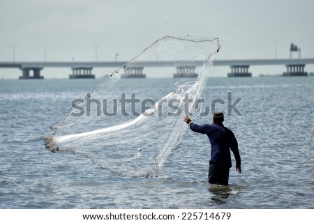 Fisherman throwing his net beside the penang second bridge
