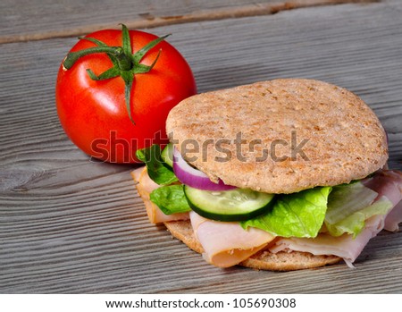 Turkey sandwich on whole wheat with onion, cucumber, lettuce and tomato on old vintage wood table