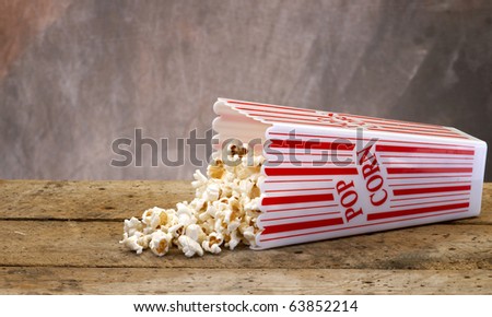 Popcorn in a container ready for the movies or your next project, on Old vintage wood table top with tan muted background.