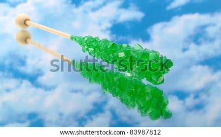 Green rock candy with stick on a cloud background with reflection