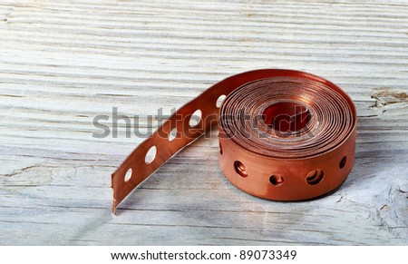 Brass Pipe Hanger Strap on vintage wood table top with warm background