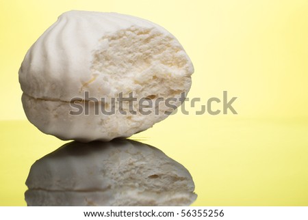Bitten white marshmallow on reflective surface