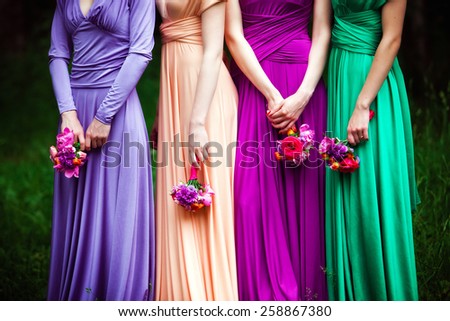 Bridesmaids in colorful dresses with bouquets of flowers