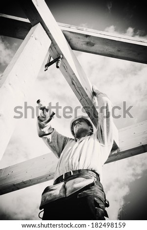 carpenter with hammer working on timber construction. Monochrome