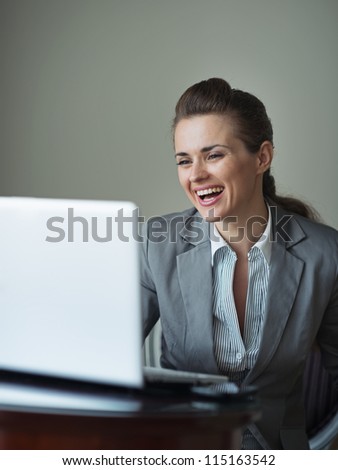 Smiling business woman in hotel room looking in laptop