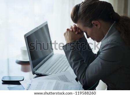 Stressed business woman working sitting at desk in hotel room