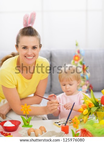 Happy mother and baby painting on Easter eggs