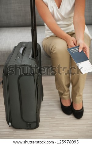 Closeup on suitcase and woman holding passport and air ticket