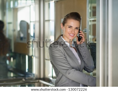 Smiling business woman talking cell phone in elevator