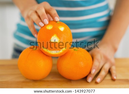 Closeup on orange with funny face in hand of young woman