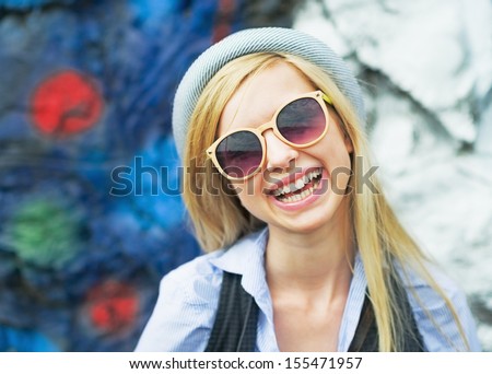 Portrait of smiling hipster girl wearing sunglasses outdoors