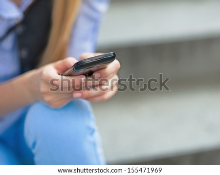 Closeup on hipster girl writing sms while sitting on stairs