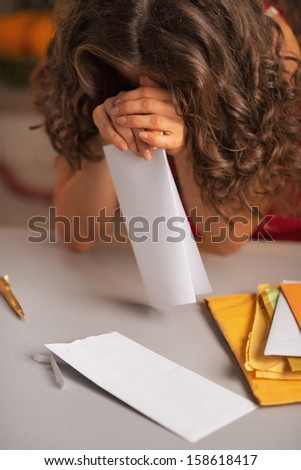 Closeup on stressed young housewife with letter