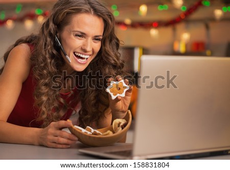 Smiling young woman showing christmas cookies while having video chat on laptop
