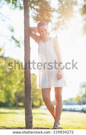 Portrait of smiling young woman standing near seedling tree