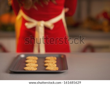 Closeup on pan with christmas cookies and housewife in background