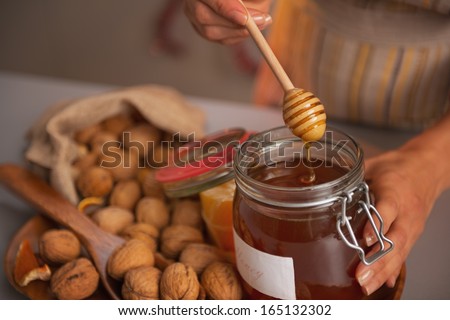 Closeup on young woman putting honey dipper in honey jar