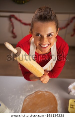 Portrait of smiling young housewife rolling pin