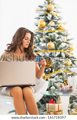 Young woman making online shopping near christmas tree