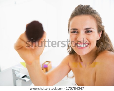Happy young woman using makeup brush