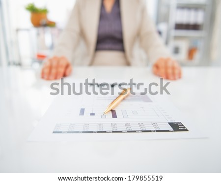 Closeup on document on table and business woman in background