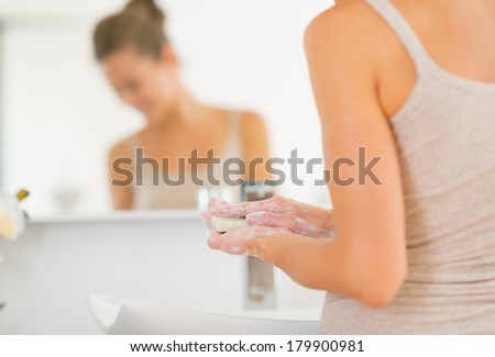 Closeup on young woman washing hands in bathroom with soap bar