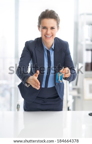 Happy business woman giving keys and stretching hand for handshake