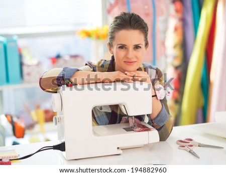 Portrait of happy seamstress with sewing machine