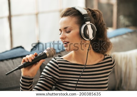 Portrait of young woman singing with microphone in loft apartment