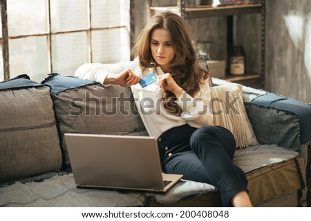 Young woman with credit card using laptop in loft apartment