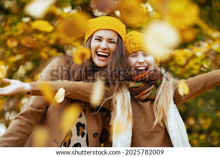 Hello september. happy young mother and child in yellow hats outdoors on the city park in autumn rejoicing.