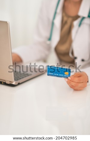 Closeup on medical doctor woman with credit card using laptop