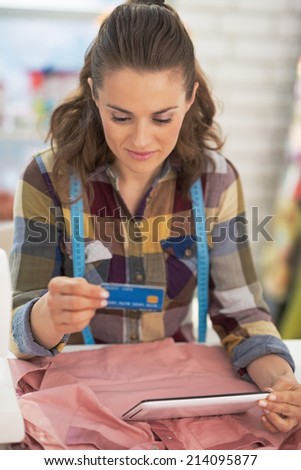 Portrait of tailor woman with credit card using tablet pc at work