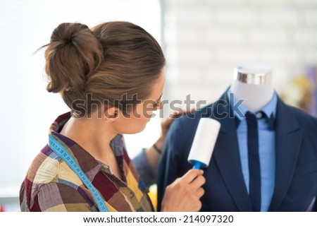 Tailor woman cleaning business suit. rear view