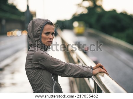 Portrait of fitness young woman looking into distance in rainy city