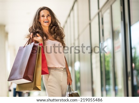 Portrait of happy young woman with shopping bags on the mall alley