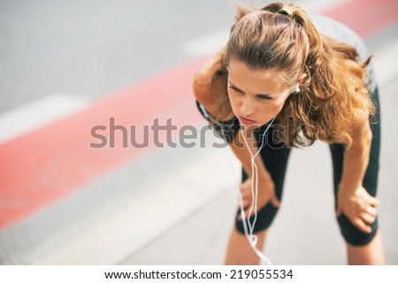 Portrait of tired fitness young woman outdoors in the city catching breathe
