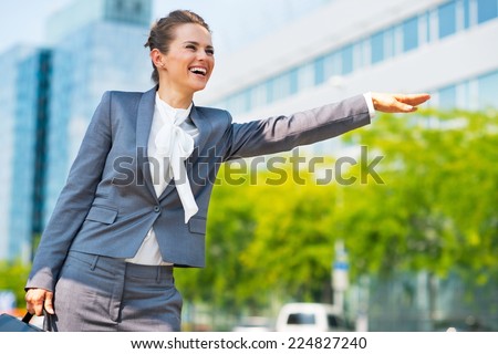 Portrait of happy business woman in office district catching taxi